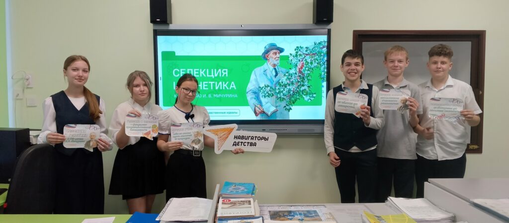 Шесть школьников стоят в классе, держат сертификаты. На стене экран с изображением человека, держащего цветы, и надписью «Селекция». Шесть школьников стоят в классе, держат сертификаты. На стене экран с изображением человека, держащего цветы, и надписью «Селекция».