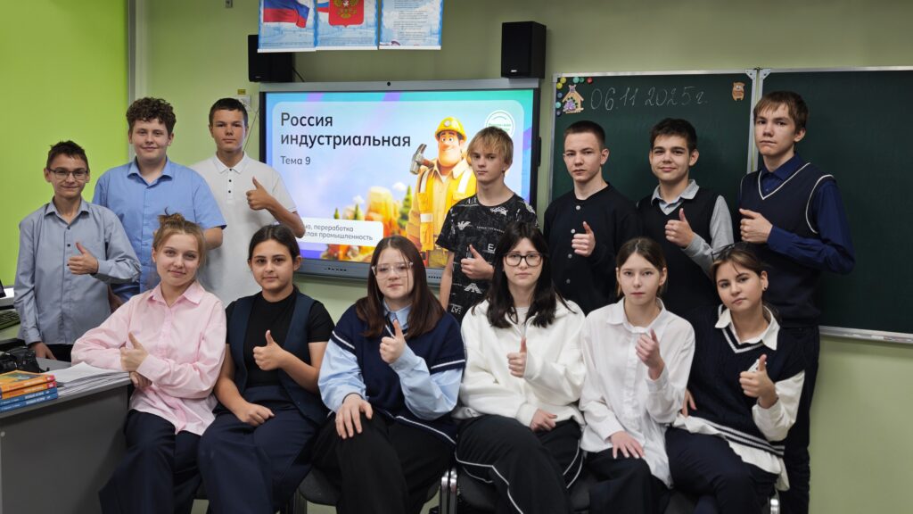 На изображении группа школьников в классе. На стене экран с надписью «Россия индустриальная». Дети показывают жест «всё хорошо». На изображении группа школьников в классе. На стене экран с надписью «Россия индустриальная». Дети показывают жест «всё хорошо».
